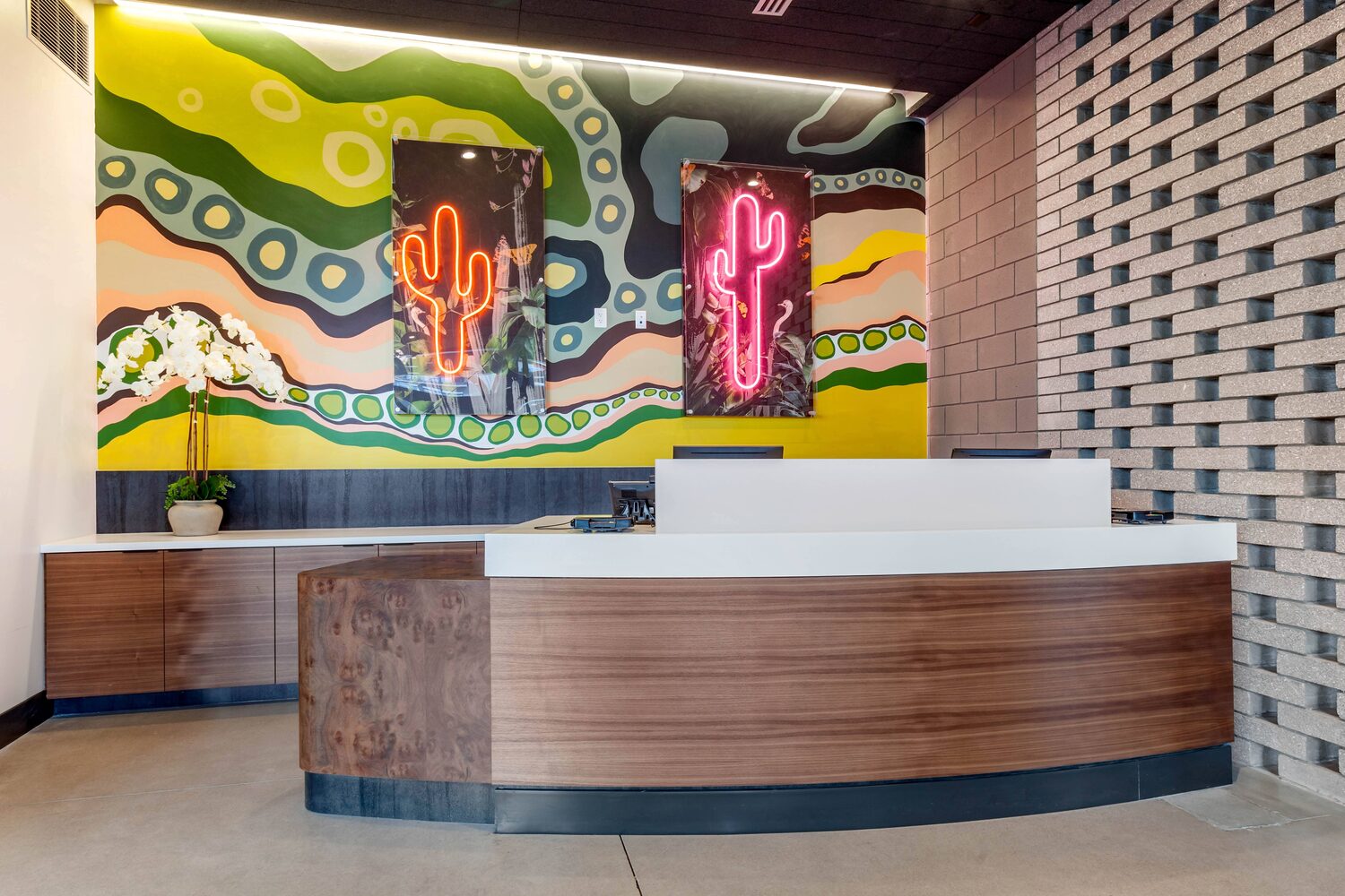 Arrival desk beneath a neon and mural treatment in the lobby